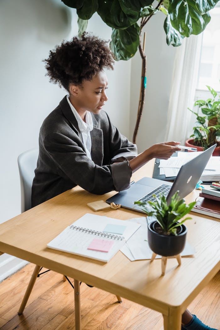 services-01 African American businesswoman engaged in remote work, using a laptop at a home office desk.